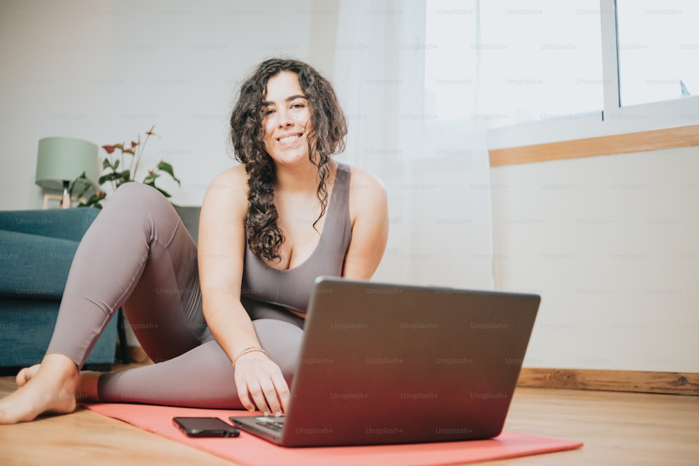 a woman sitting on the floor with a laptop