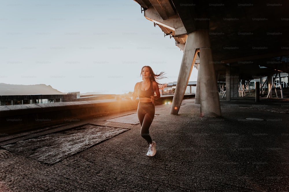 uma mulher correndo sob uma ponte ao pôr do sol