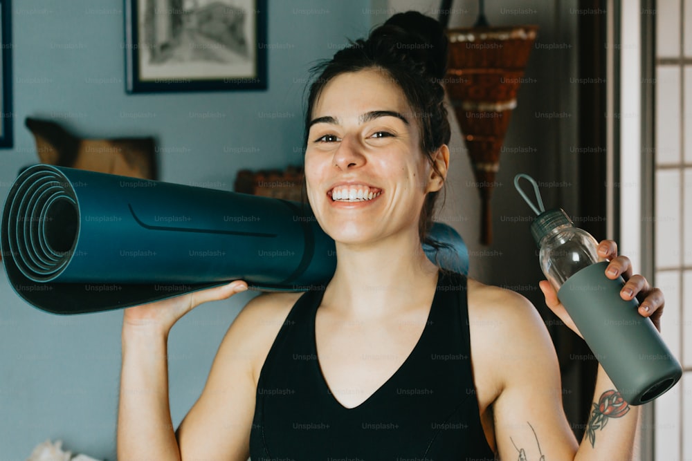a woman holding a yoga mat and a water bottle