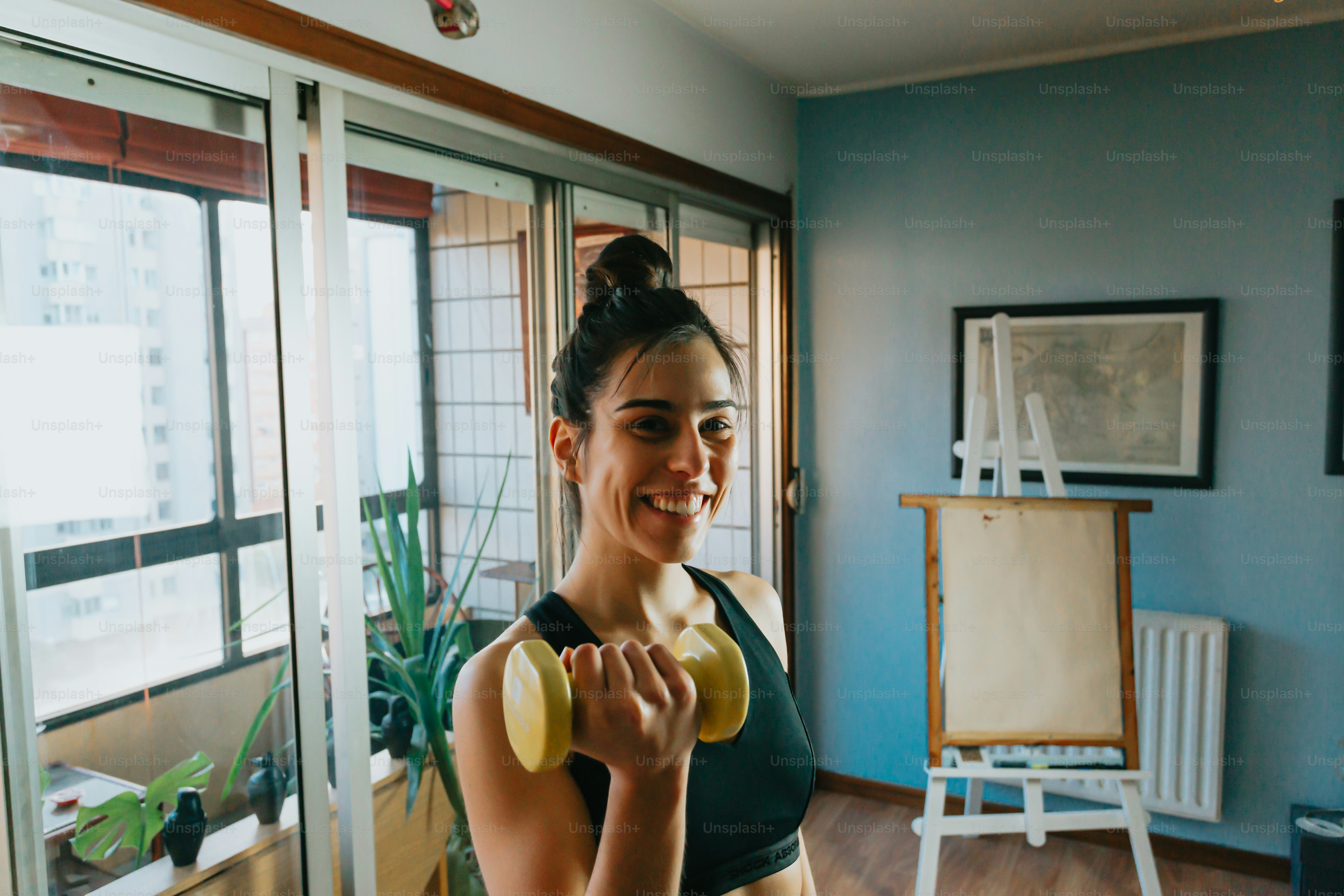 a woman holding a pair of yellow dumbs