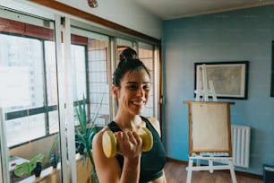 a woman holding a pair of yellow dumbs