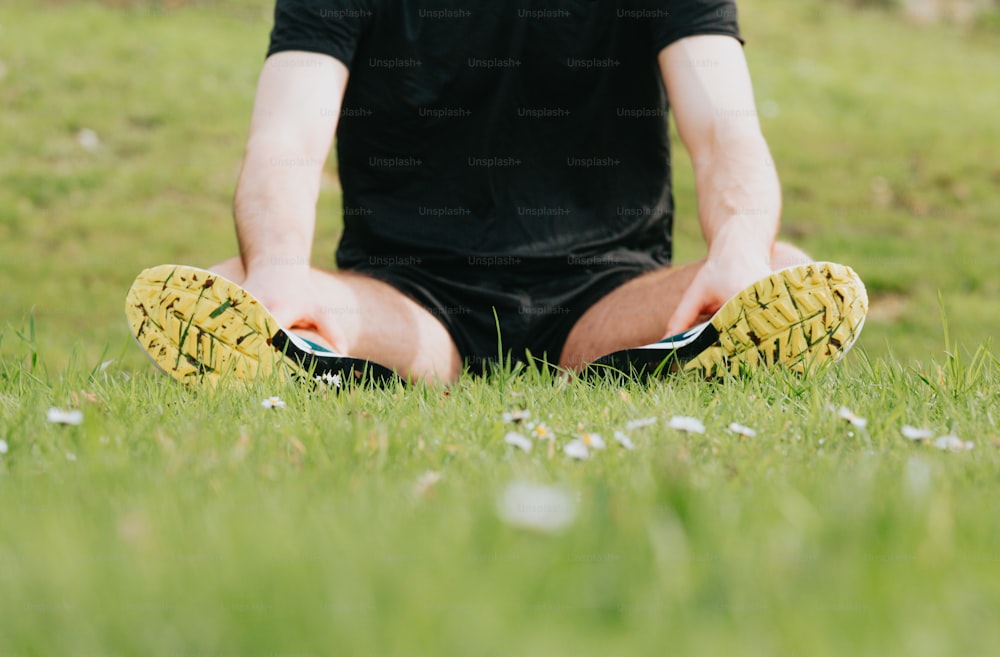 a man sitting in the grass with his feet crossed