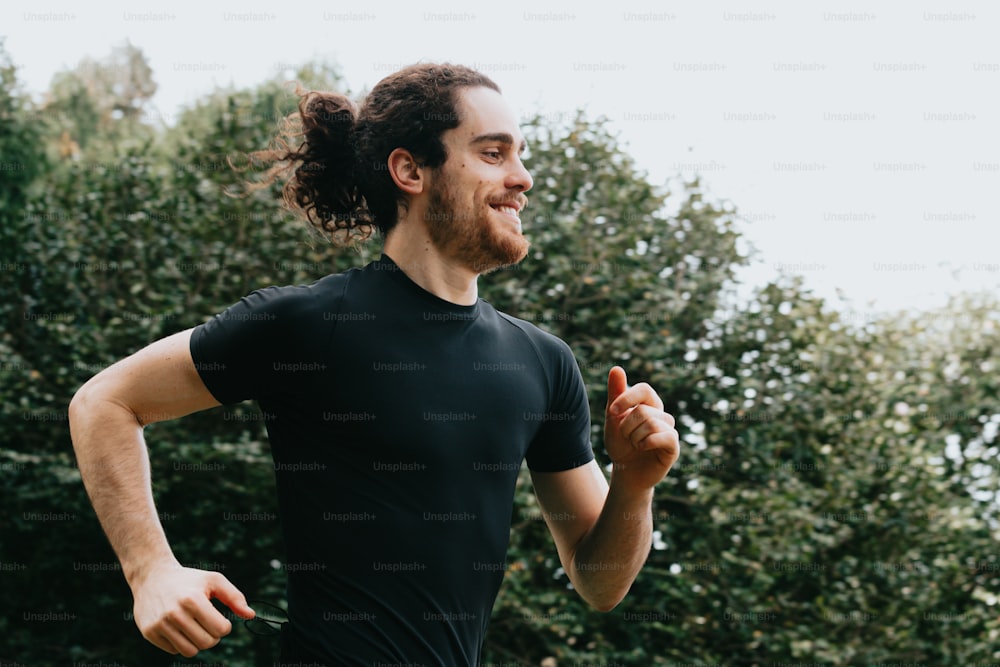a man with a ponytail running in a park