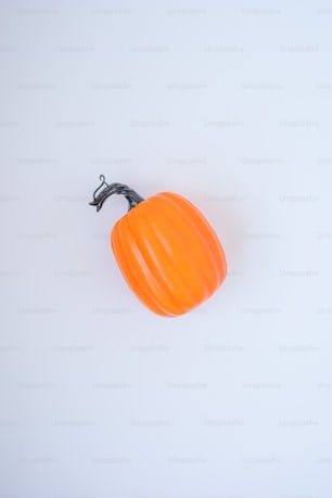 a small orange pumpkin sitting on top of a white table