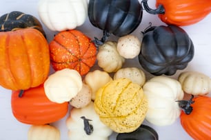 a pile of fake pumpkins and gourds on a white surface