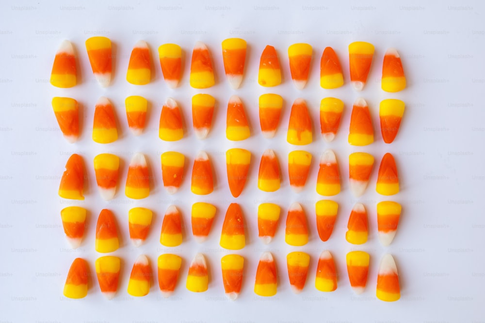 a group of orange and white candy corn on a white surface