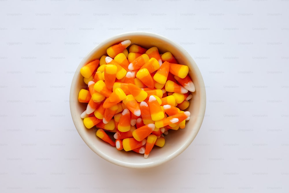 a bowl filled with candy corn on top of a white table