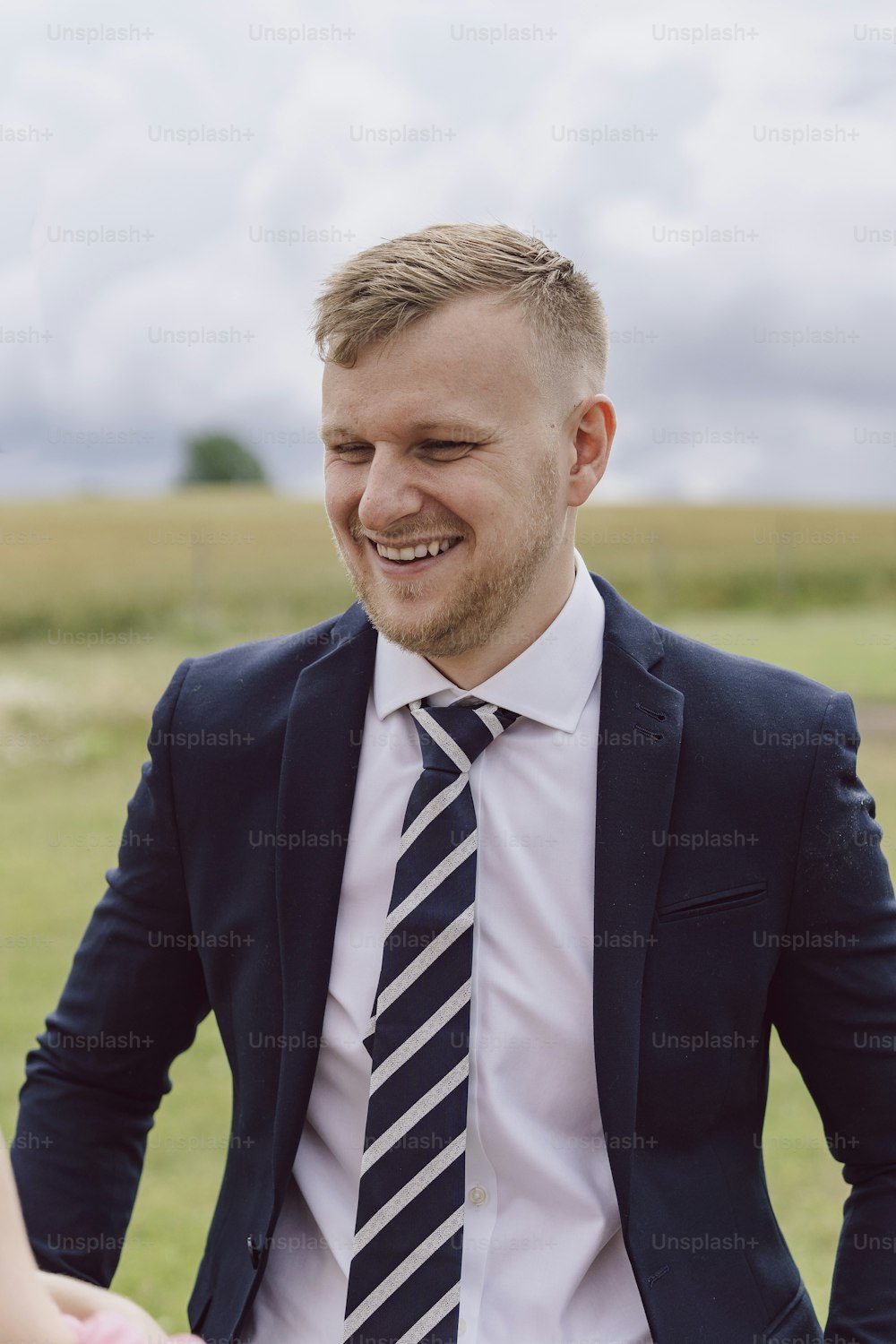 a man in a suit and tie standing in a field