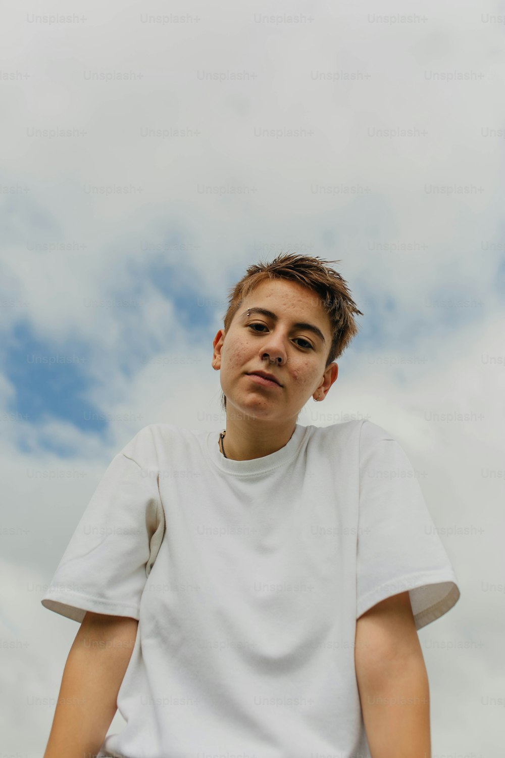 a boy in a white t - shirt looks up at the sky