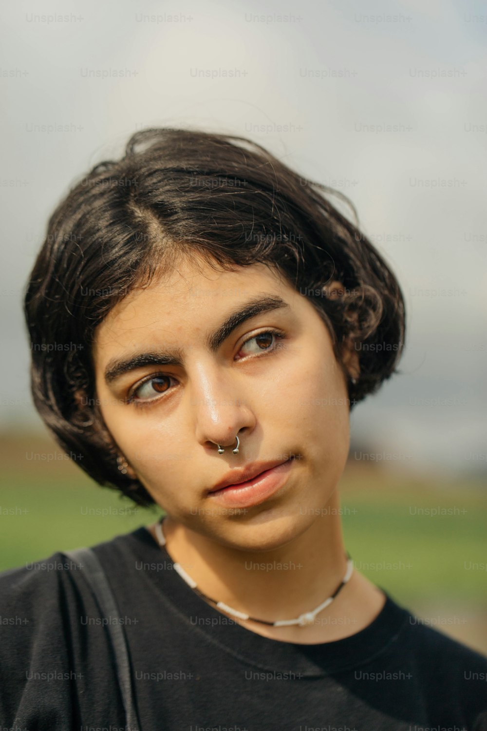 a young man with a nose piercing looking at the camera
