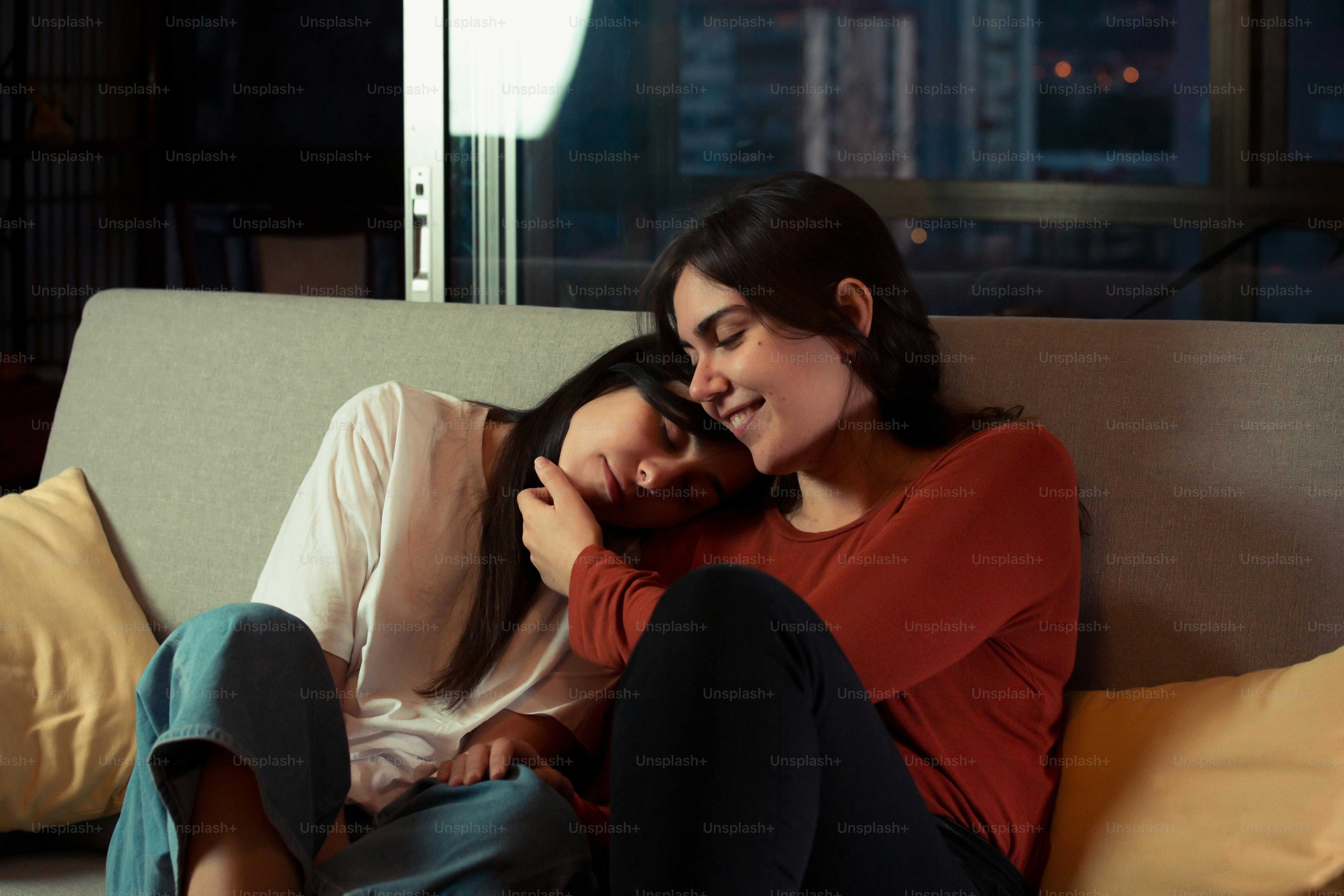 a couple of women sitting on top of a couch