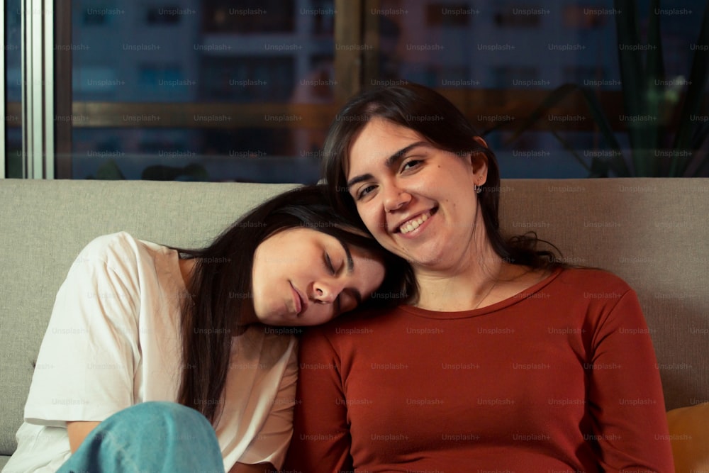 um casal de mulheres sentadas uma ao lado da outra em um sofá