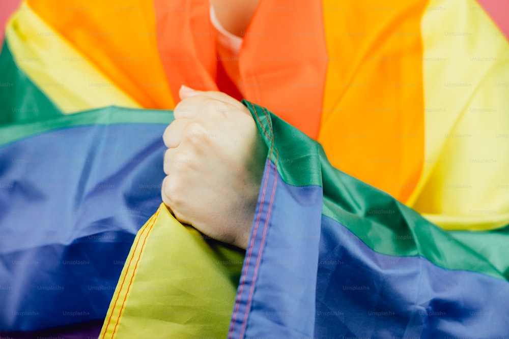 a close up of a person holding a rainbow colored kite