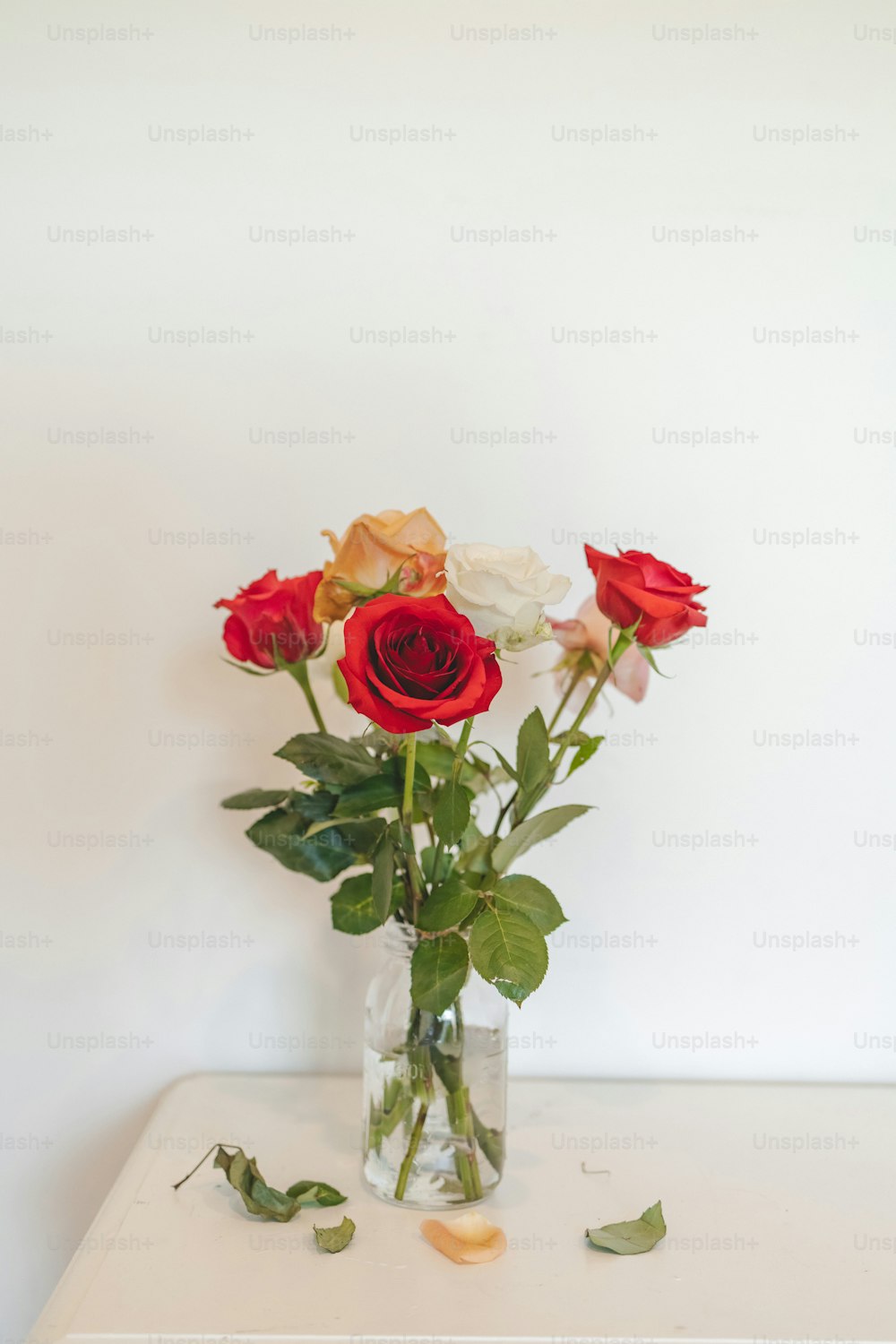 um vaso cheio de rosas vermelhas e brancas em cima de uma mesa