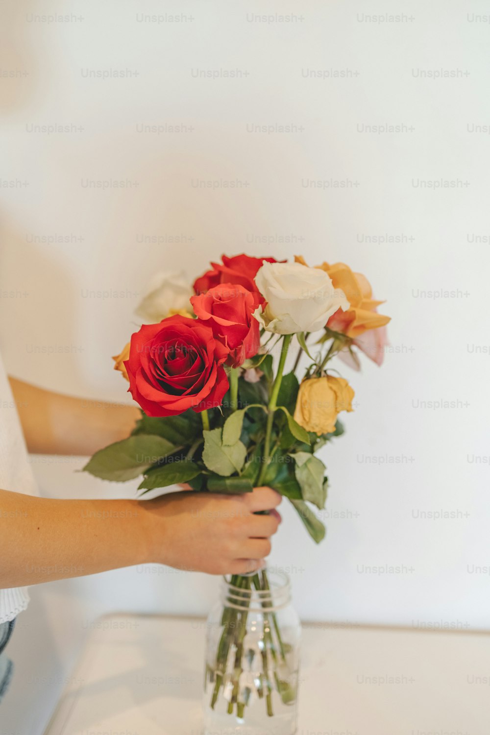 a person holding a vase of flowers on a table