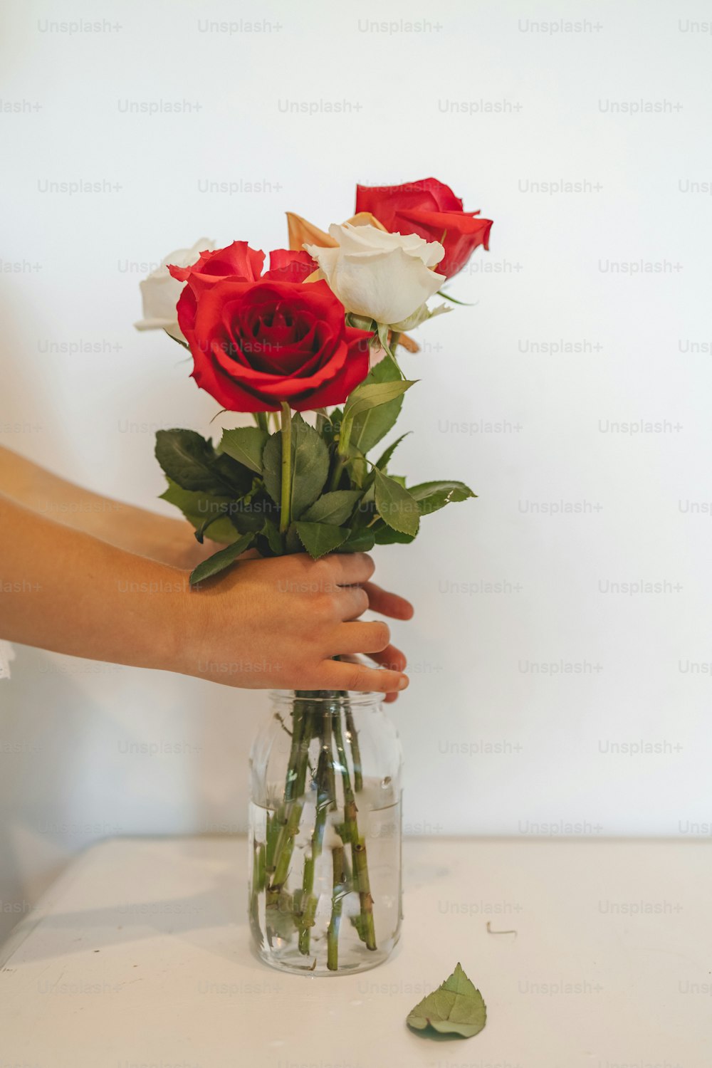 a person holding a vase with roses in it