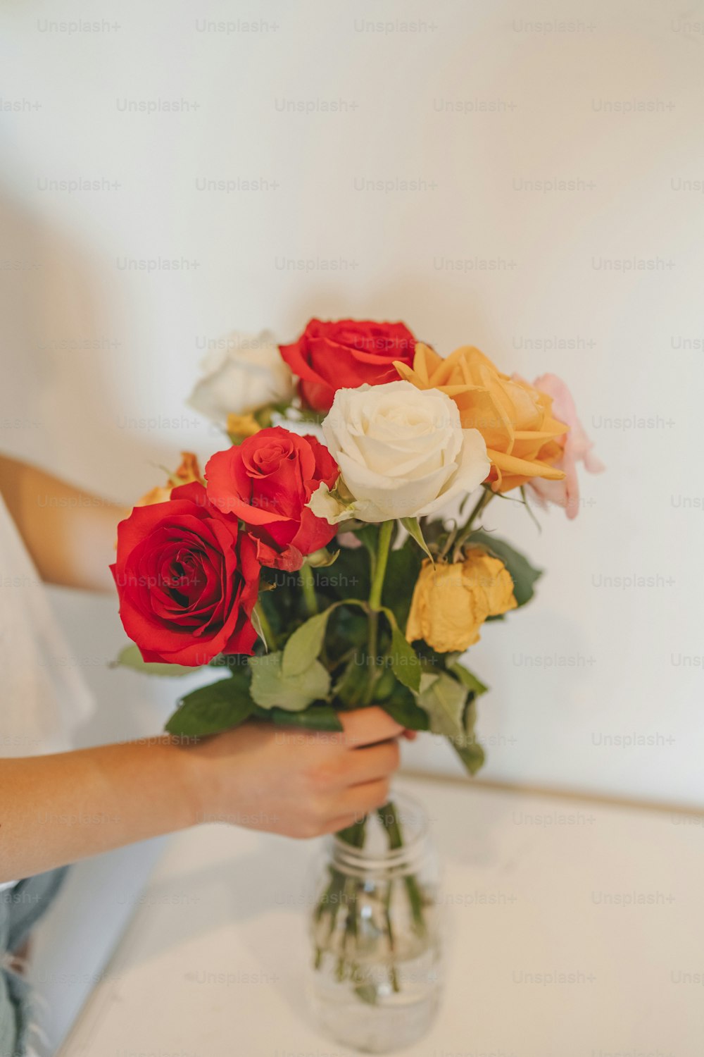 a person holding a bouquet of roses in a vase