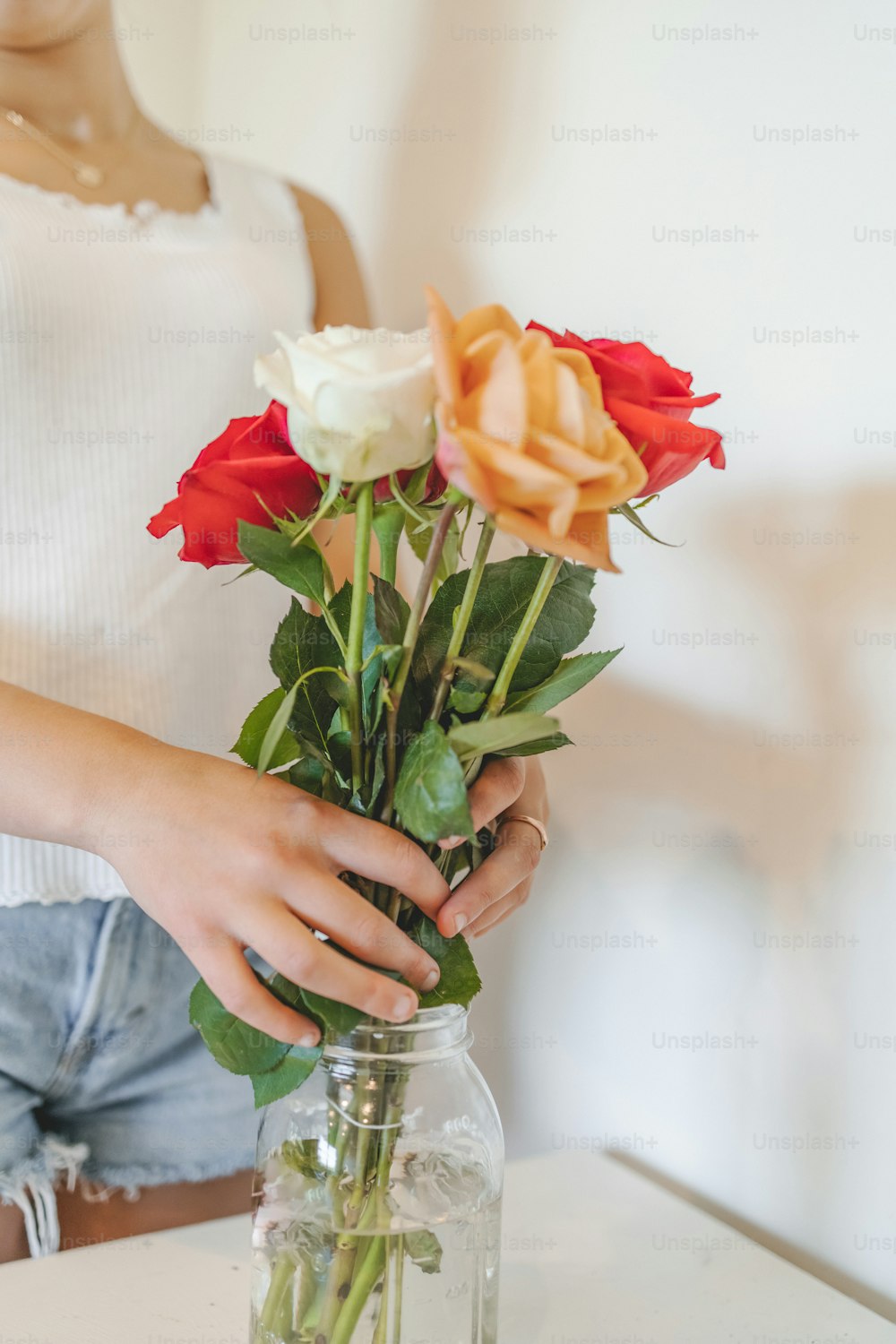 a woman is holding a vase with roses in it