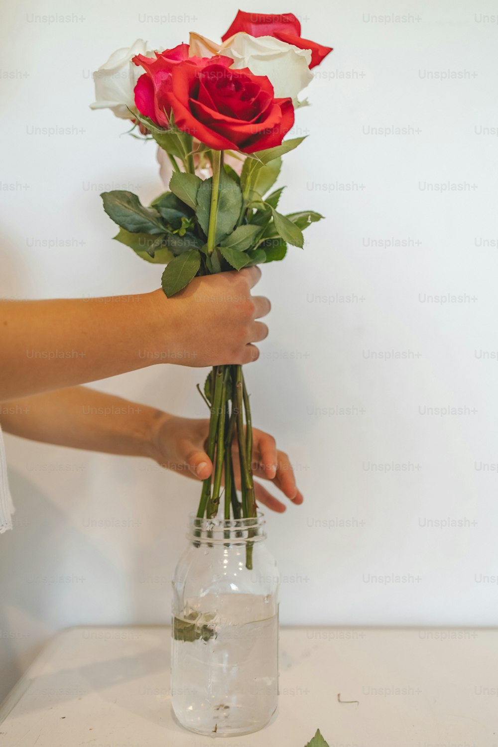 a person holding a bouquet of roses in a vase
