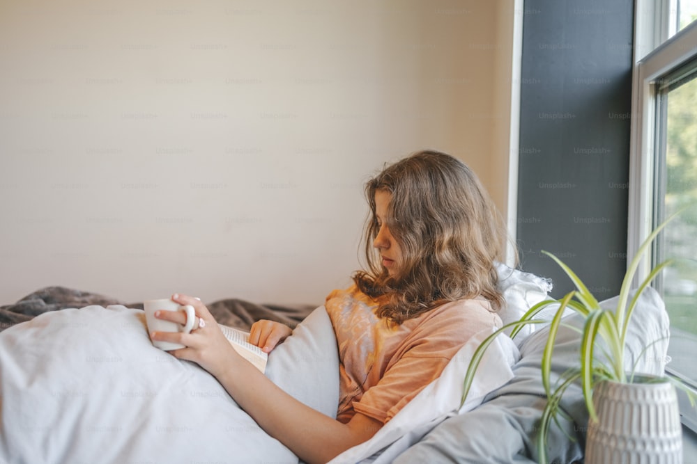 a young girl sitting on a bed reading a book