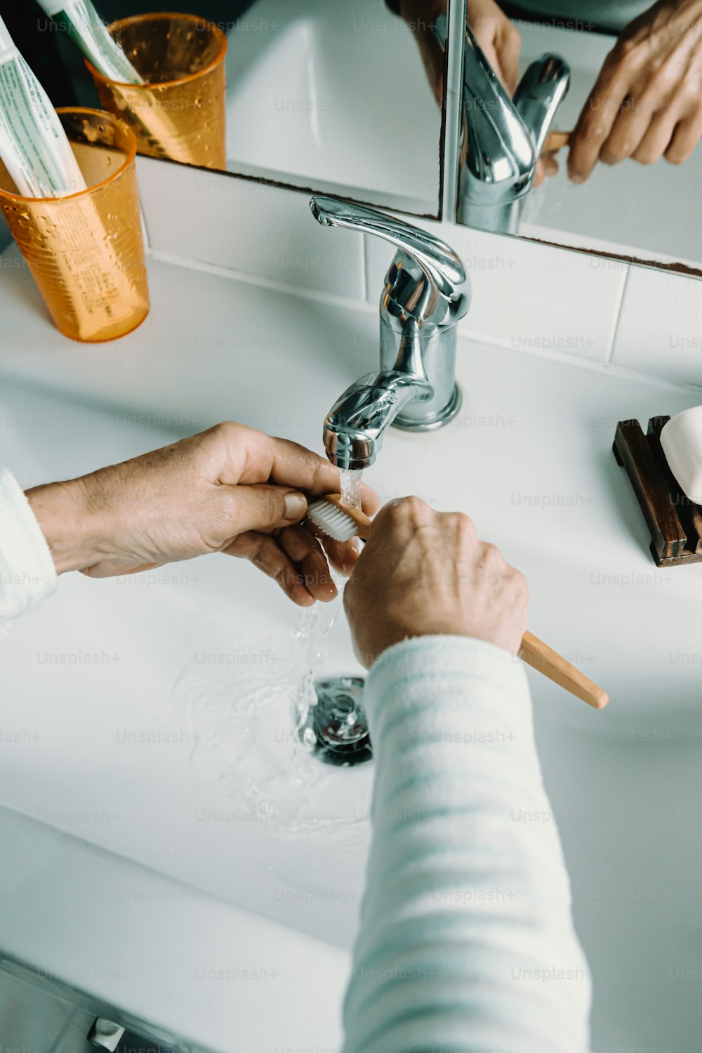 a person washing their hands under a bathroom sink