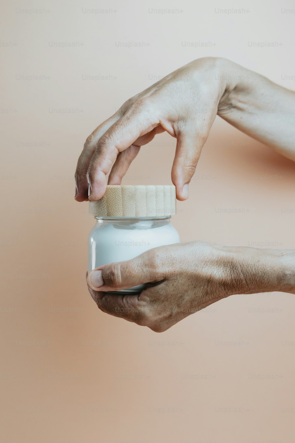a person holding a jar of cream in their hands