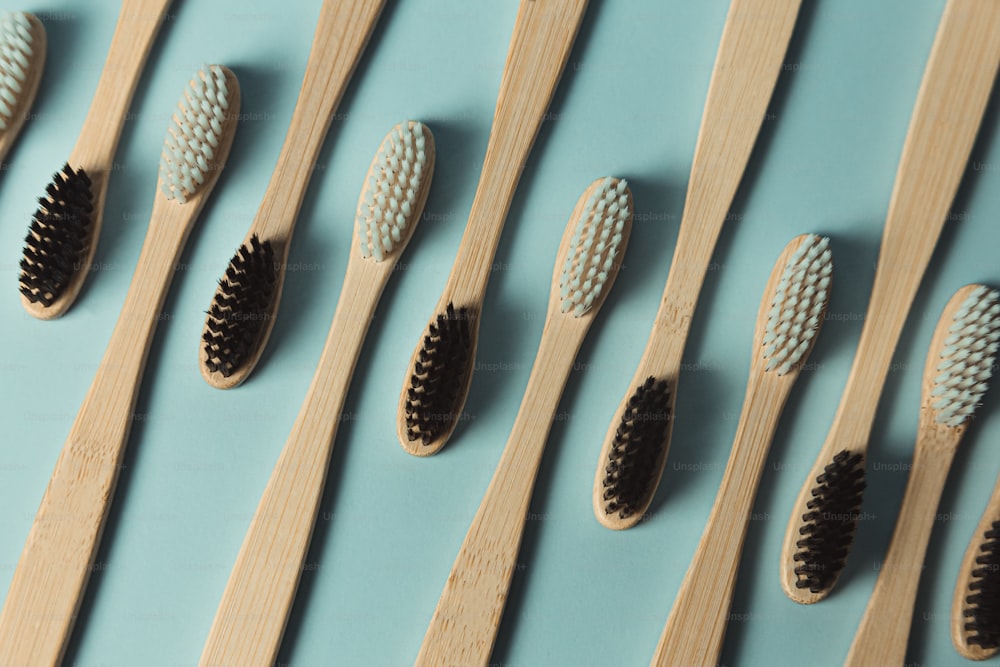 Una hilera de cepillos de dientes de madera alineados sobre una superficie azul