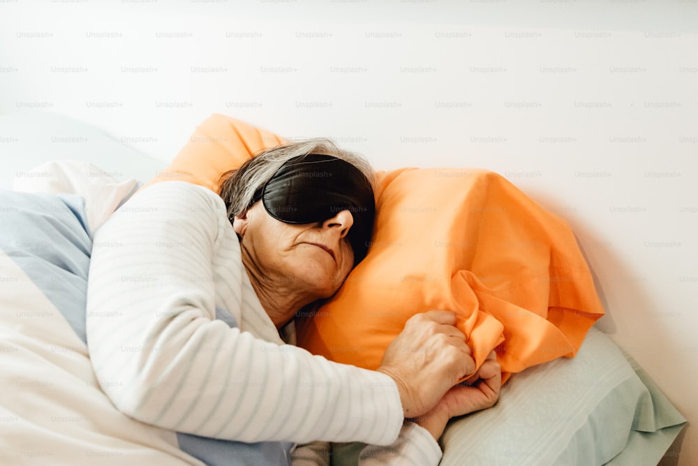 a woman laying in bed with an orange pillow