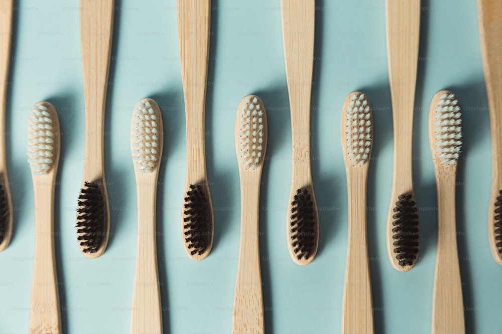 a row of wooden toothbrushes lined up against a blue wall