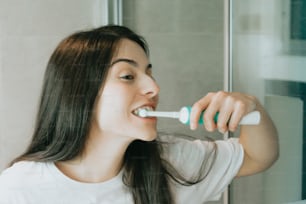 uma mulher escovando os dentes no banheiro
