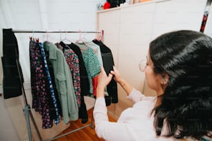 a woman looking at a rack of clothes