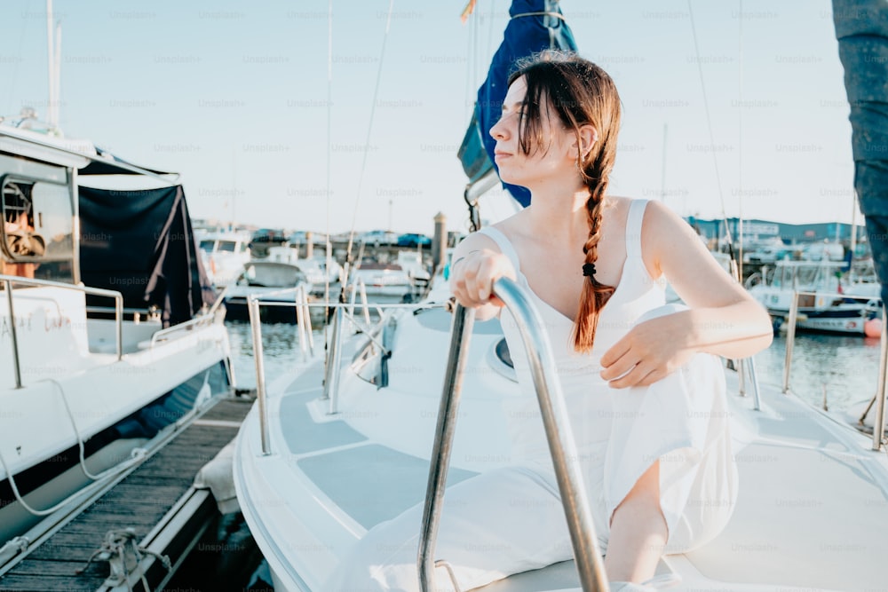 Une femme en robe blanche assise sur un bateau