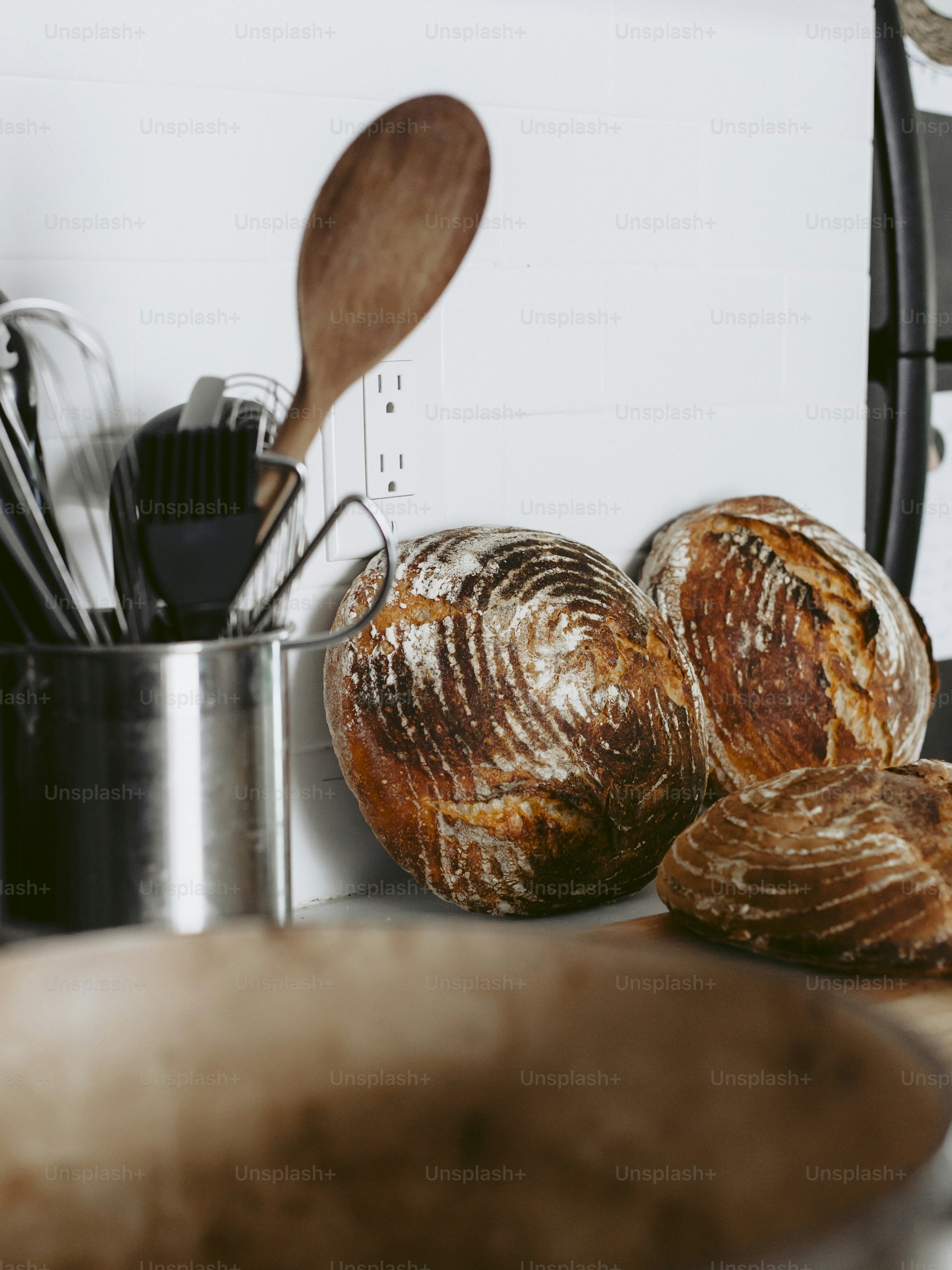 a pan filled with loaves of bread next to a wooden spoon