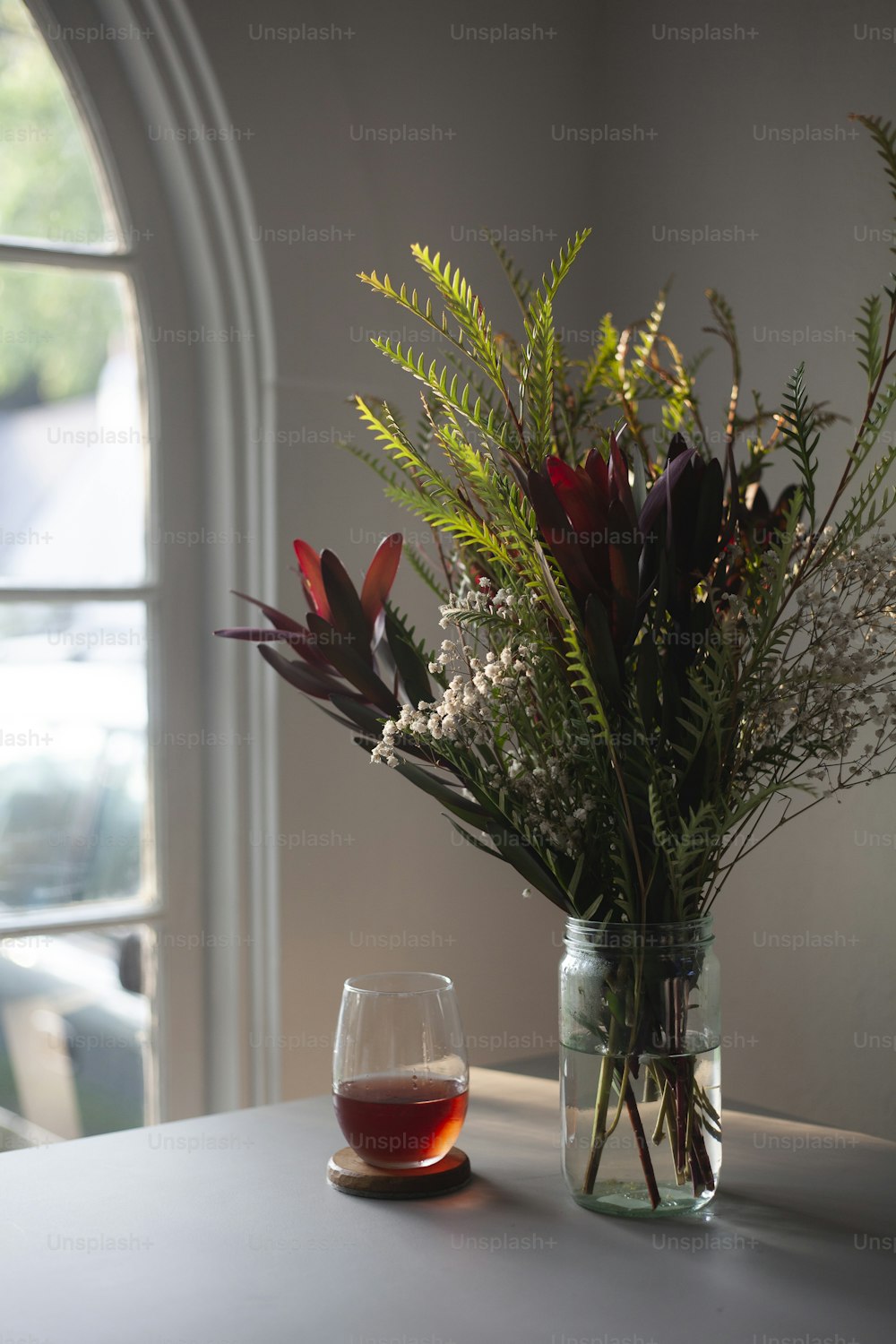 a vase of flowers and a glass of wine on a table