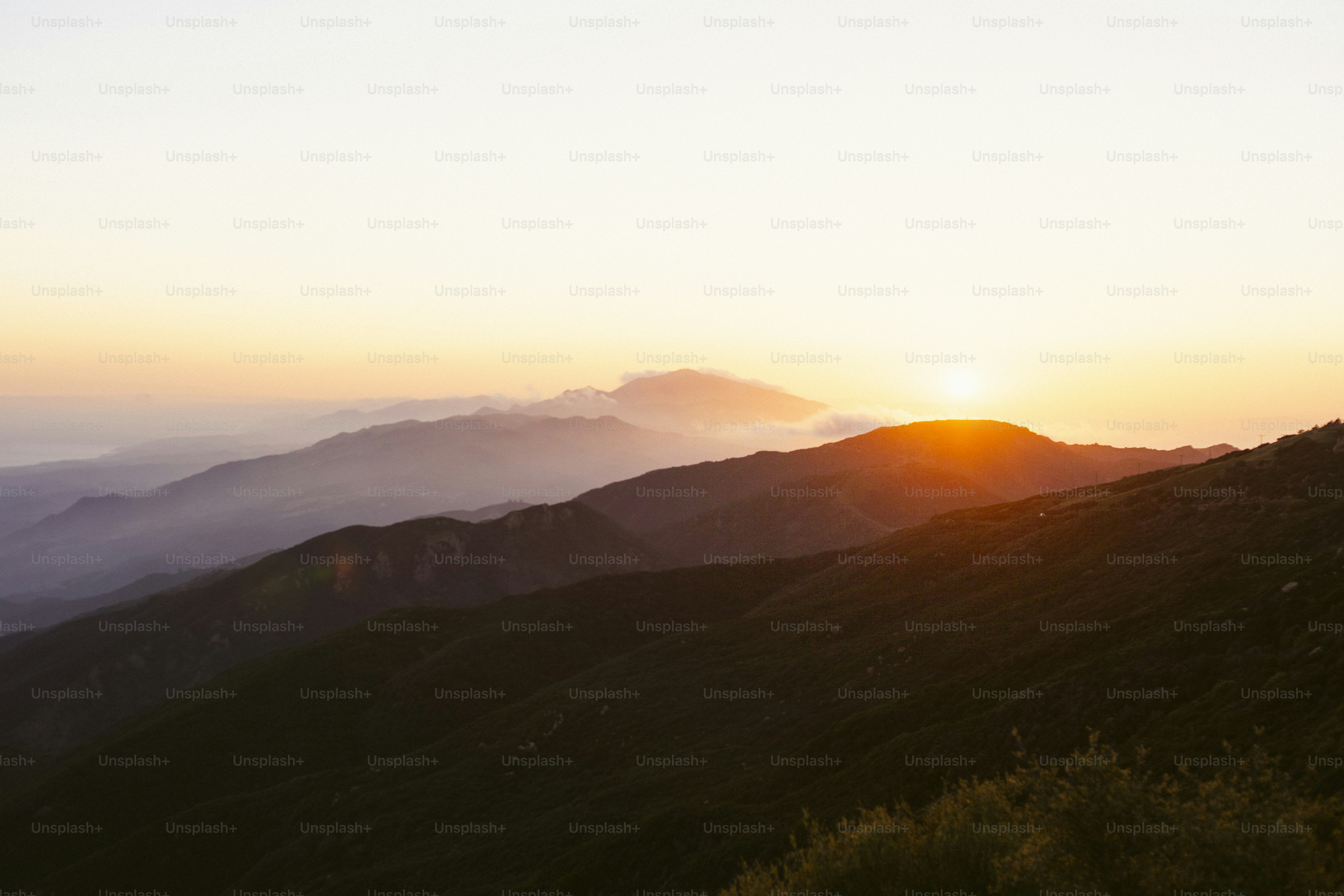 the sun is setting over the mountains in the distance