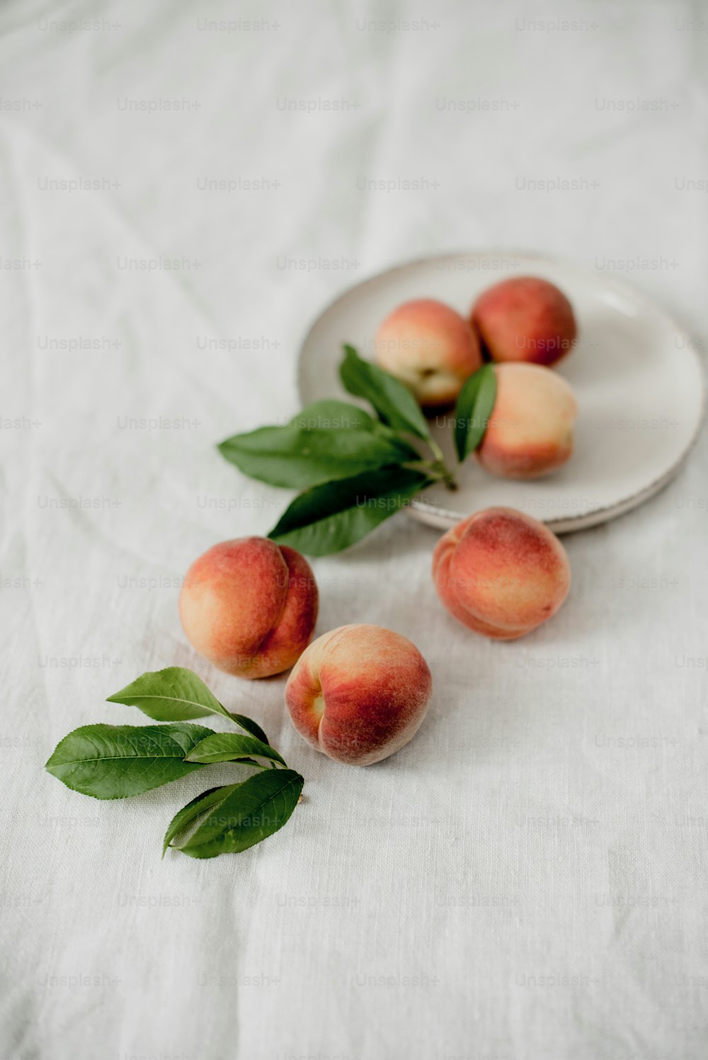 a plate of peaches on a white table cloth