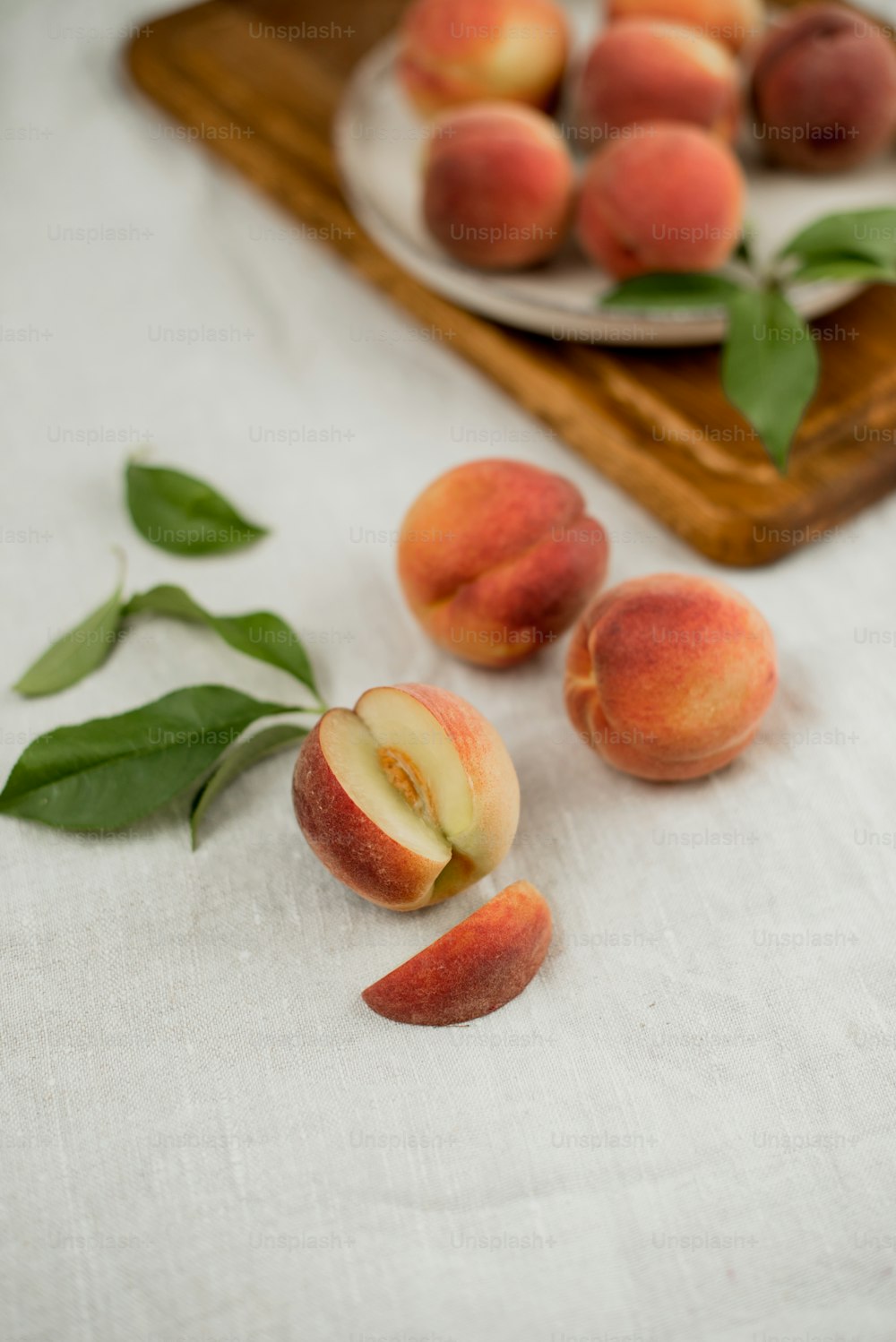 a plate of peaches on a table with leaves