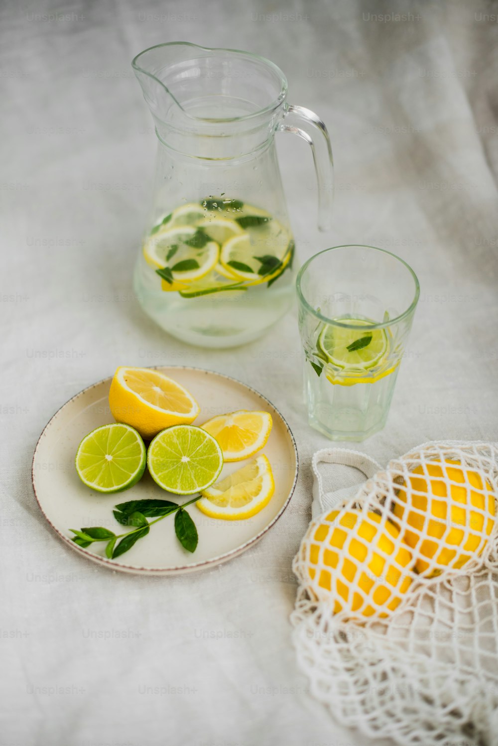 a plate of lemons and limes next to a pitcher of water