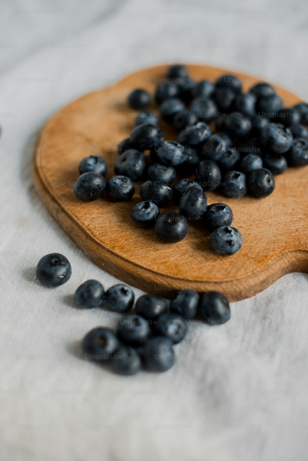 a wooden spoon filled with blueberries on top of a table
