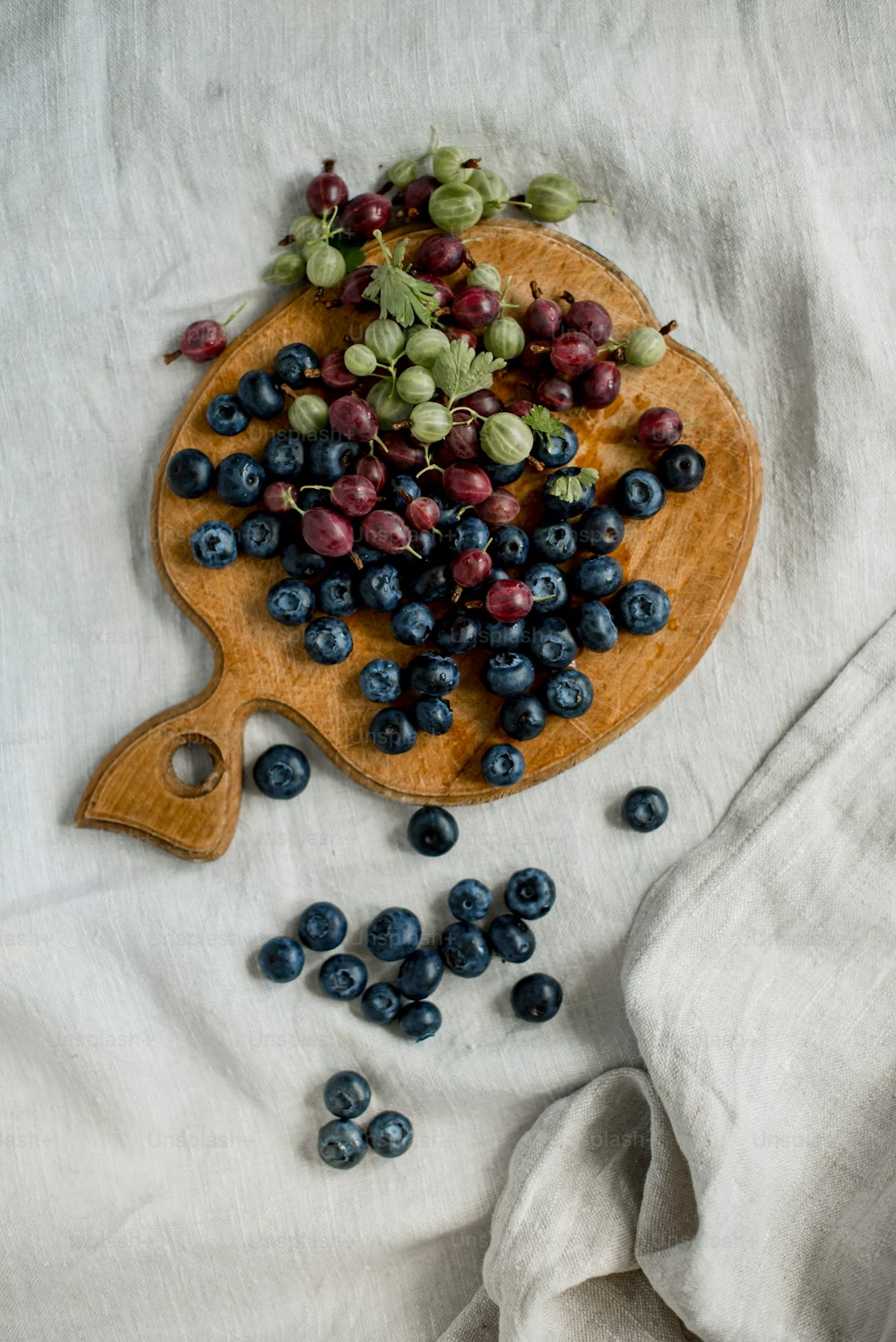 a wooden cutting board topped with blueberries and grapes
