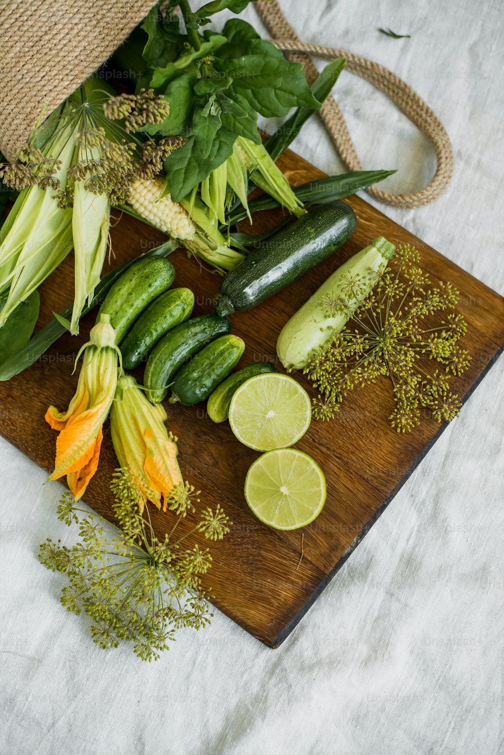 a wooden cutting board topped with cucumbers and limes