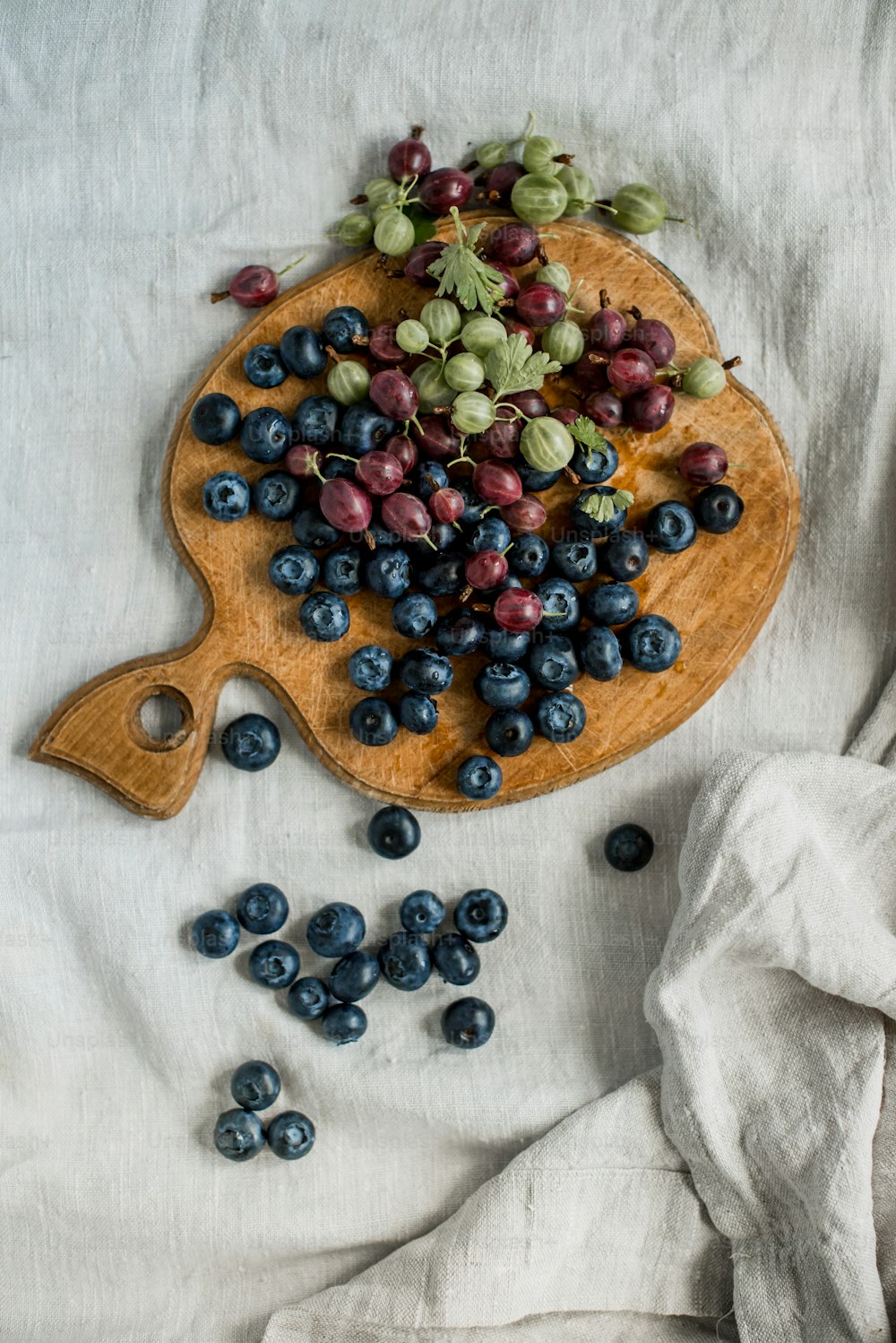 a wooden cutting board topped with blueberries and grapes
