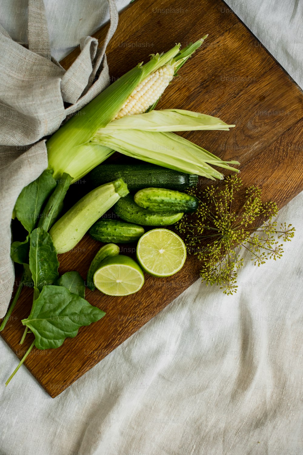 a wooden cutting board topped with cucumbers and other vegetables
