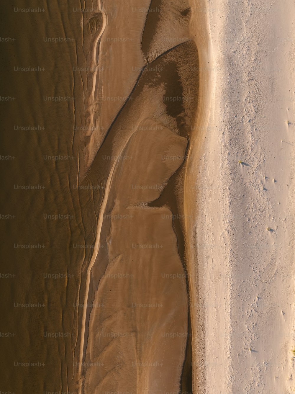 an aerial view of a sandy beach and a body of water