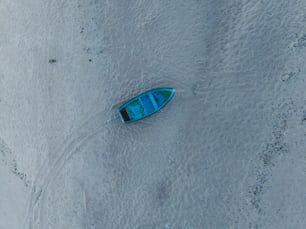 um pequeno barco azul sentado no topo de uma praia de areia