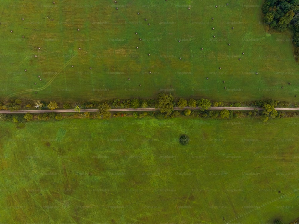 an aerial view of a road running through a green field