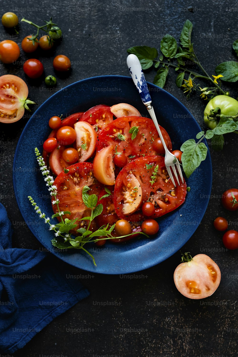 a blue plate topped with sliced tomatoes and a fork