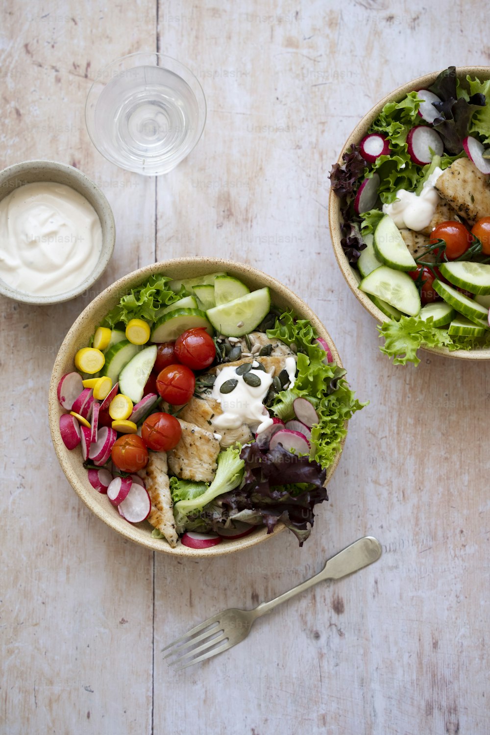 zwei Schüsseln Salat mit Dressing an der Seite