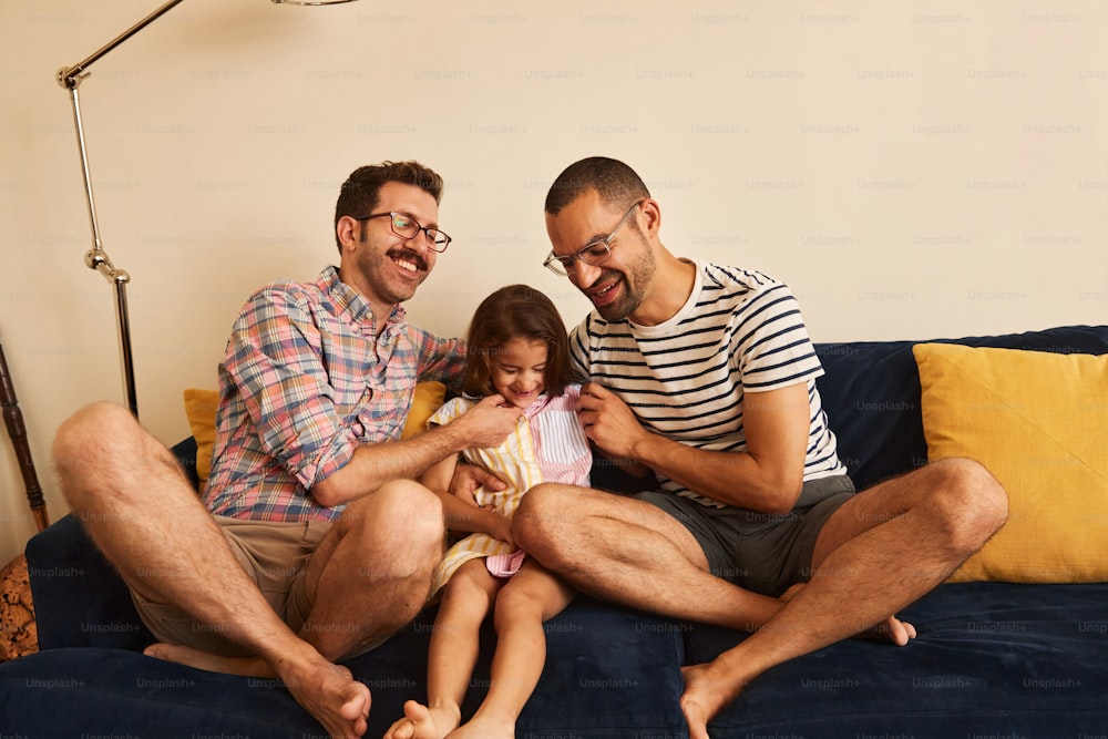 two men and a little girl sitting on a couch