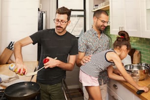 a man and two young girls cooking in a kitchen